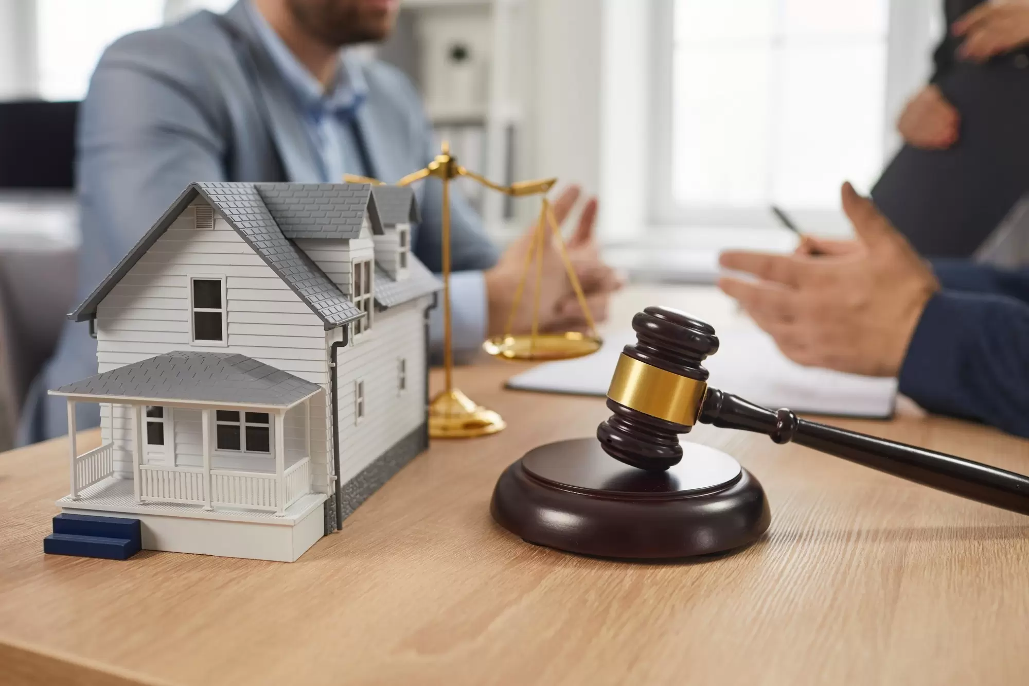 Group of people meeting and talking at office table with gavel and residential house model. Close up closeup judge hammer and toy house on desk. Real estate, property law, legal lawyer service concept.