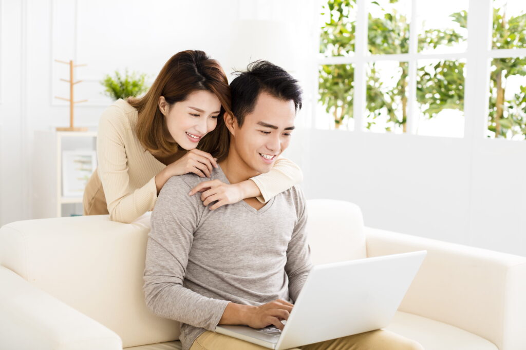 happy young couple using laptop on sofa